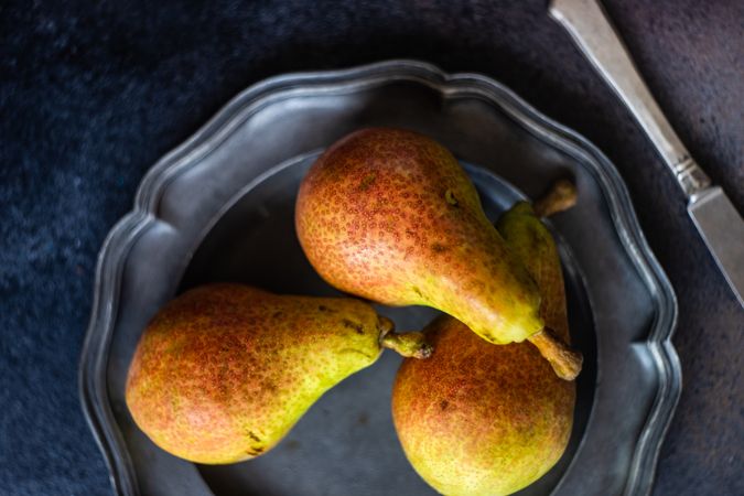Top view of three pears on dark plate