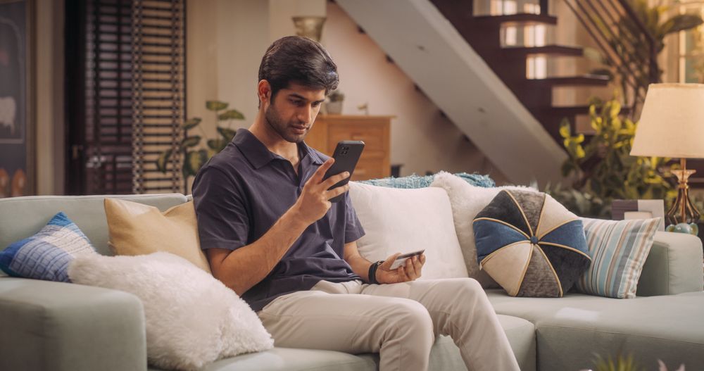 Indian Man Using Credit Card and Smartphone for Online Shopping at Home.