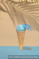 Blue ice cream in cone with cocktail parasol on beach background 42wygb