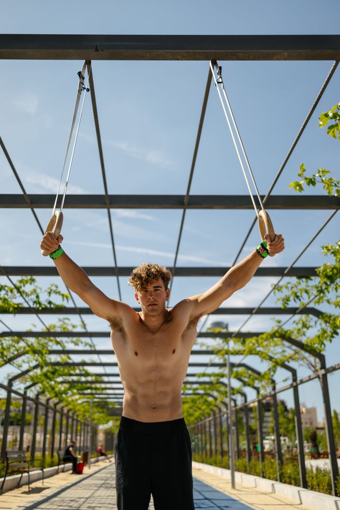Strong young sportsman exercising with rings