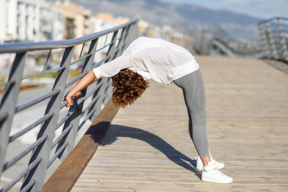 Woman doing bridge stretch on railing