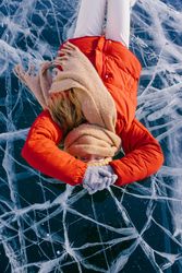 Happy woman in skates lying on ice