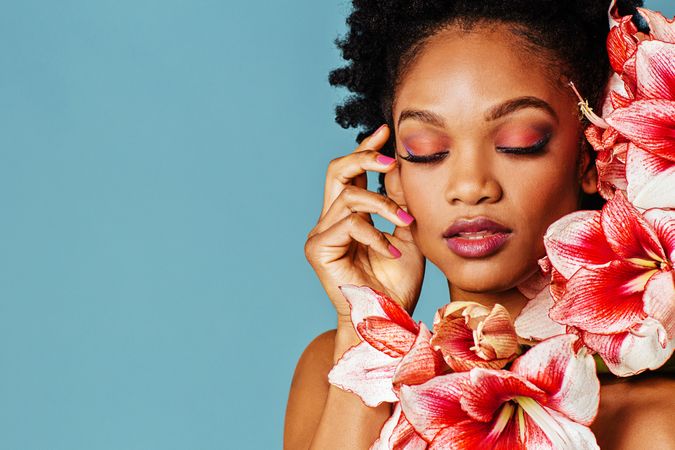 Studio shoot of Black woman surrounded by flowers with copy space