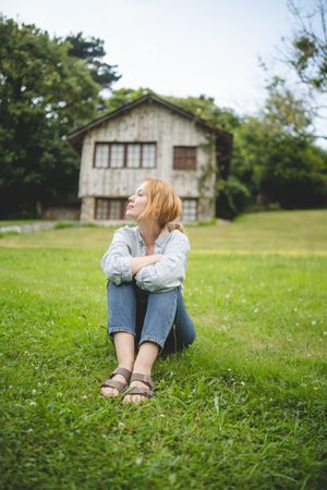 Content female sitting on grass in countryside