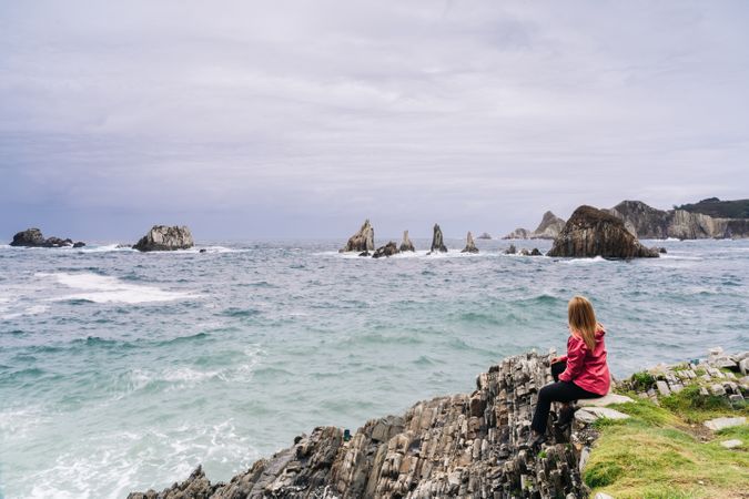 Woman sitting on stony green seashore