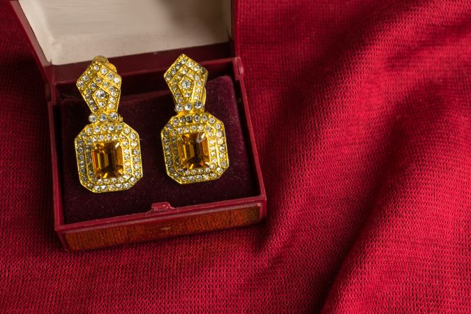 Beautiful shiny golden earrings with diamond studded Indian traditional design on a red velvet background