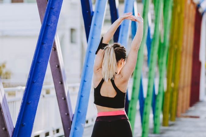 Woman with earphones stretching hands on street