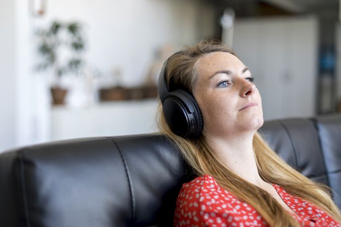 Woman at home sitting on couch wearing headphones