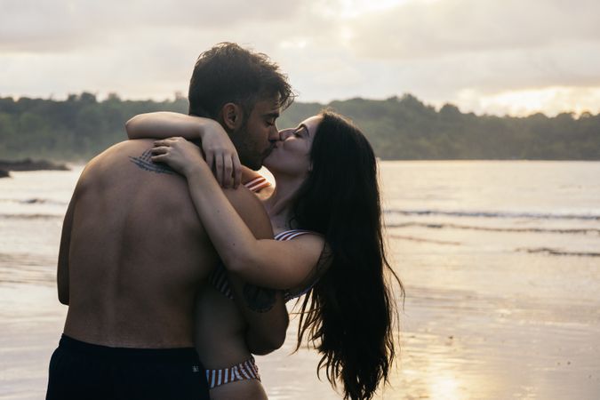 Couple kissing on the beach at sunset