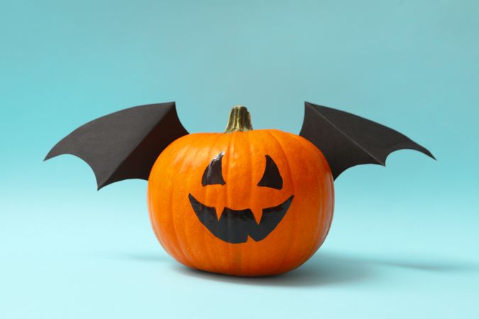 Pumpkin with smile and wings on blue background