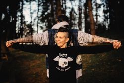 Young guy and happy woman standing back to back in forest