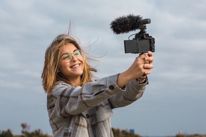 Happy female blogger shooting video on camera