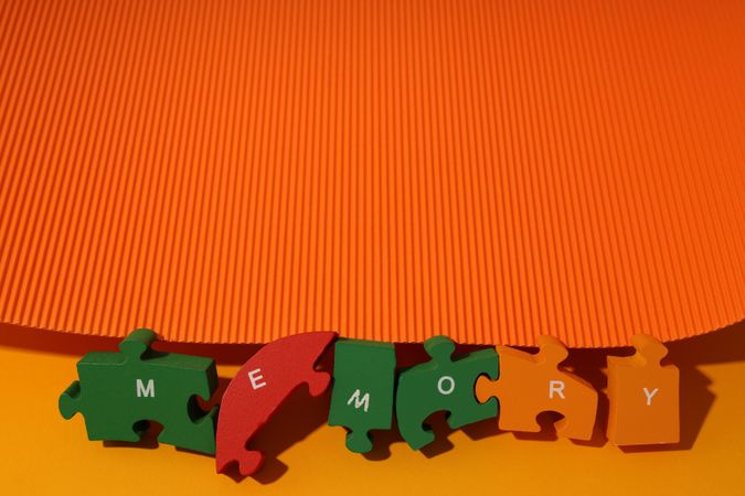 Orange background with puzzle pieces spelling out the word “Memory”