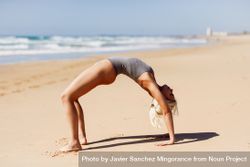 Woman doing bridge on sand on a Spanish beach 5k76W5