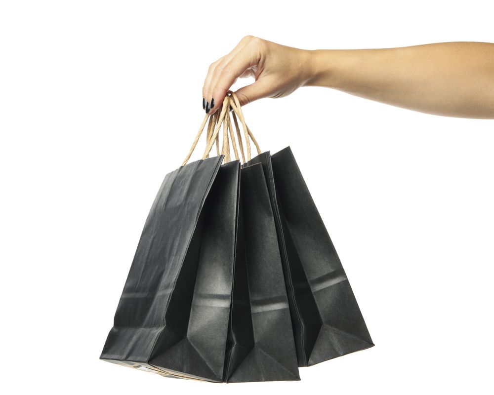 Female hand hold paper bags, isolated on light background
