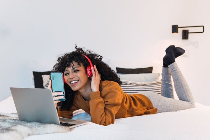 Cheerful Black female with laptop and smartphone