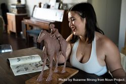Woman in tank top smiling while sculpting horse and rider 4BaMW5