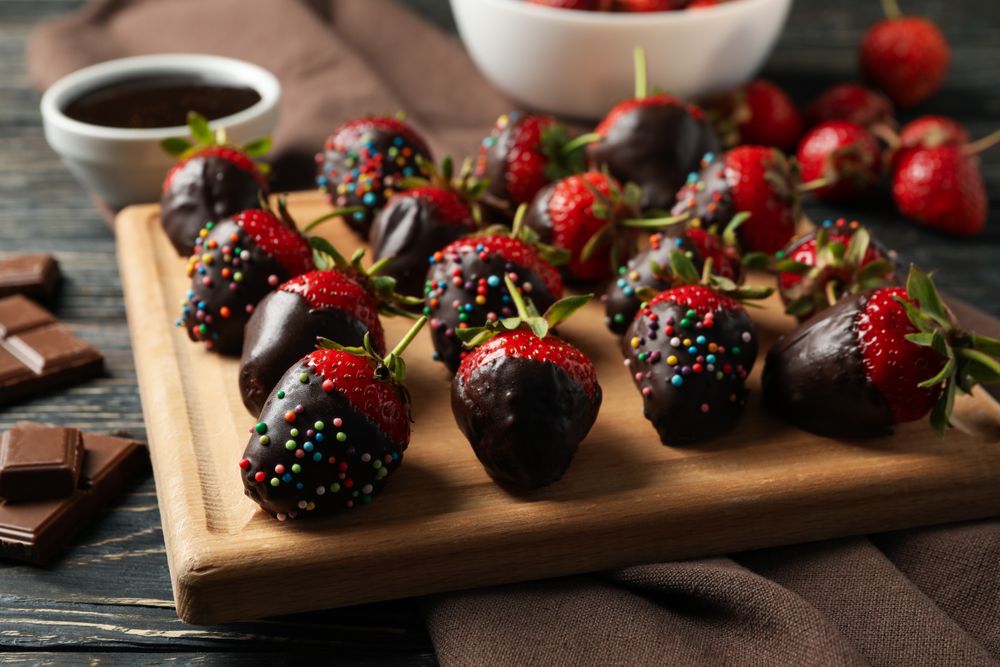 Chocolate fondue. Strawberry in chocolate on wooden background, close up
