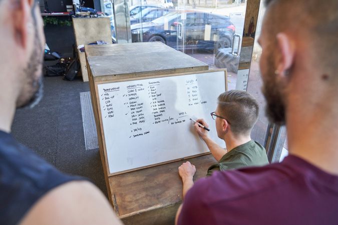 Unrecognizable men writing on whiteboard
