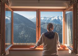 Anonymous woman looking at mountains from window
