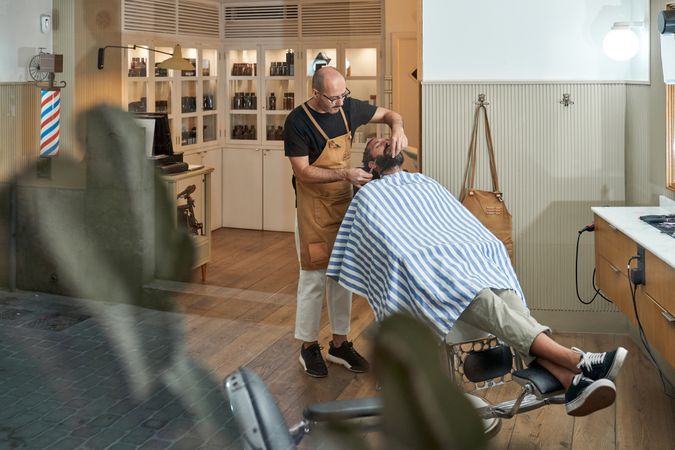 Hairdresser cutting hair of customer in barbershop