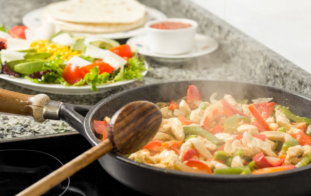 Pan cooking vegetables and chicken in the kitchen