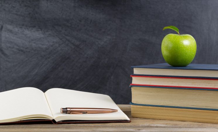 Student desk with green apple and study materials