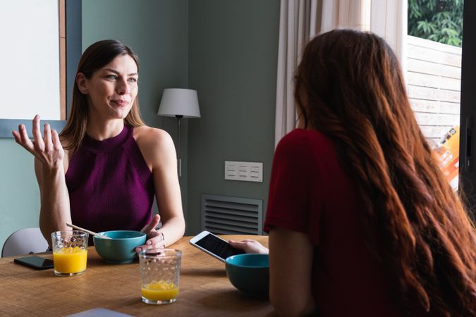 Happy women having lunch and browsing smartphone at home
