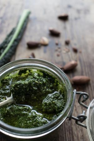 Jar with kale pesto near nuts