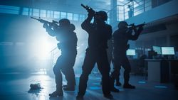 Masked Squad of Armed SWAT Police Officers in a Hall of a Dark Seized Office Building with Desks and Computers.