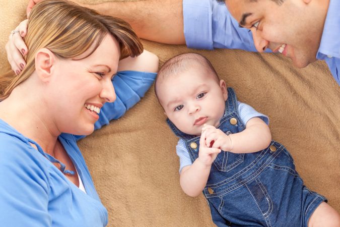 Young Couple Laying With Their Infant On A Blanket