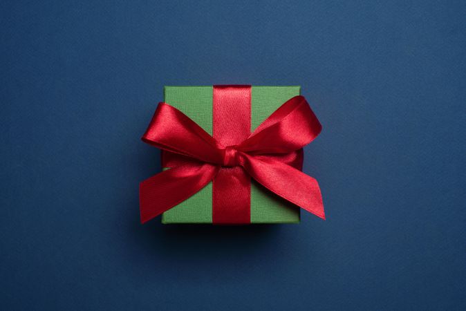 Green present wrapped with red bow on blue background