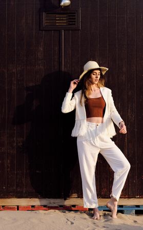 A long hair fashion model with a hat at the beach with a dark background