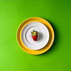 Strawberry on plate setup on green background
