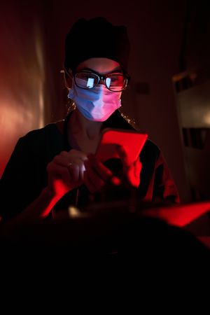 Confused doctor in mask looking at screen of cellphoneConfused d