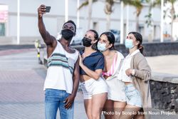 Group of women and man wearing face masks and taking selfie 4BErW5