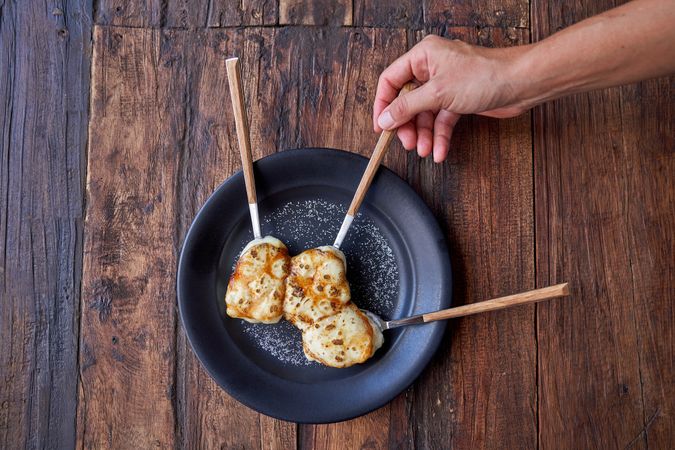Crop person with delicious pastry on wooden table
