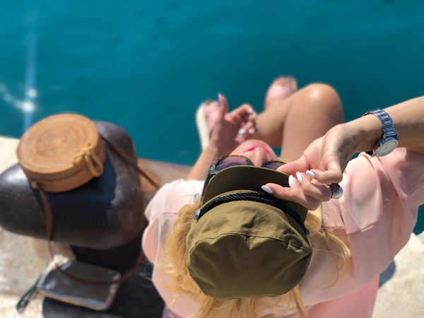 Woman wearing beret and sunglasses sitting above water