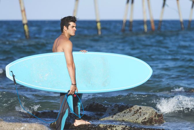 Male surfer with board walking into the water