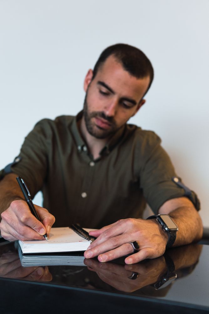Man writing in notebook near laptop