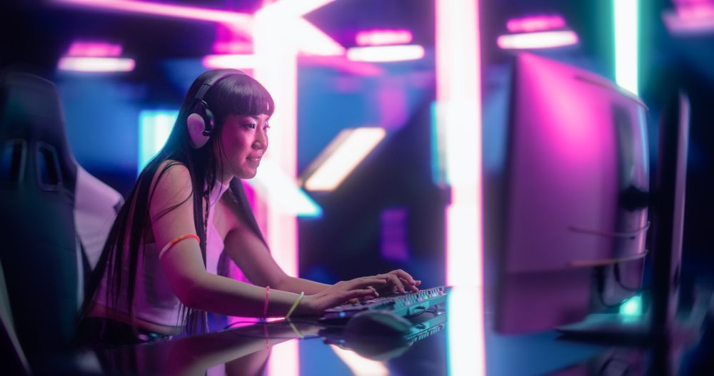 Portrait of a Japanese Young Female Wearing Headphones, Talking with Friends Online on a Computer.