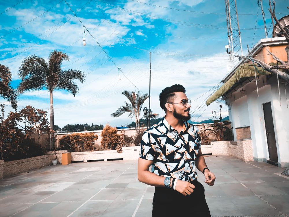 Man standing near small building and palm trees looking away
