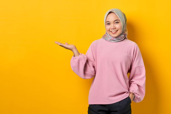 Smiling Muslim woman in scarf and presenting the copy space on her side