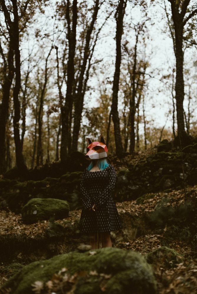 Woman in red fox mask walking in forest