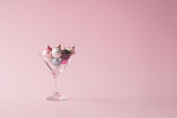 Christmas tree decoration in martini glass on pastel pink background with creative copy space