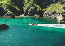 Boat driving in the sea past cliffs