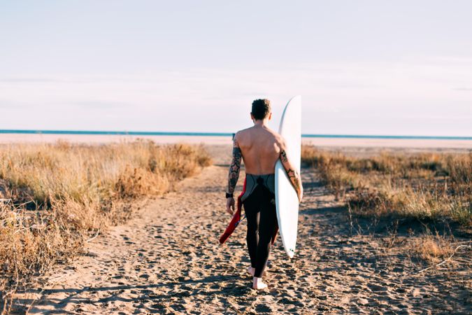 Surfer in wetsuit walking towards the beach