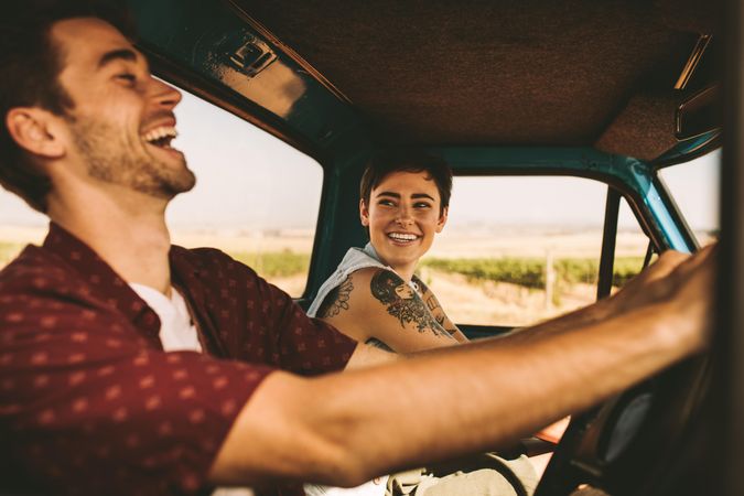 Young couple laughing and enjoying country road trip