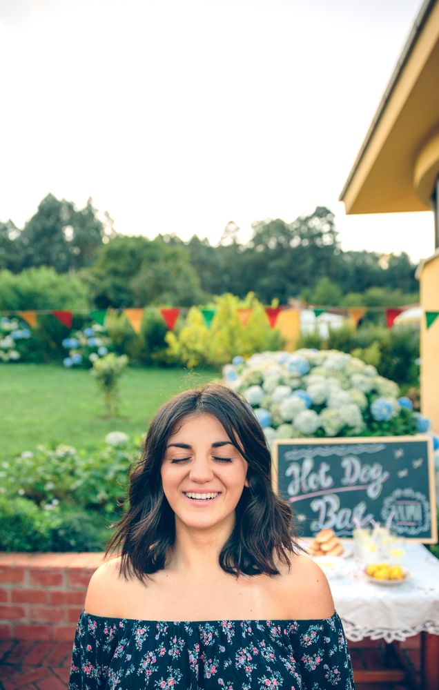 Young woman with closed eyes laughing at a backyard barbeque