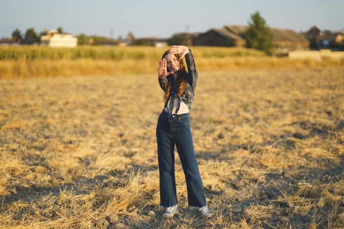 A Playful Young Girl Happily Posing in an Exquisite Sunlit Field of Lush Green Grass